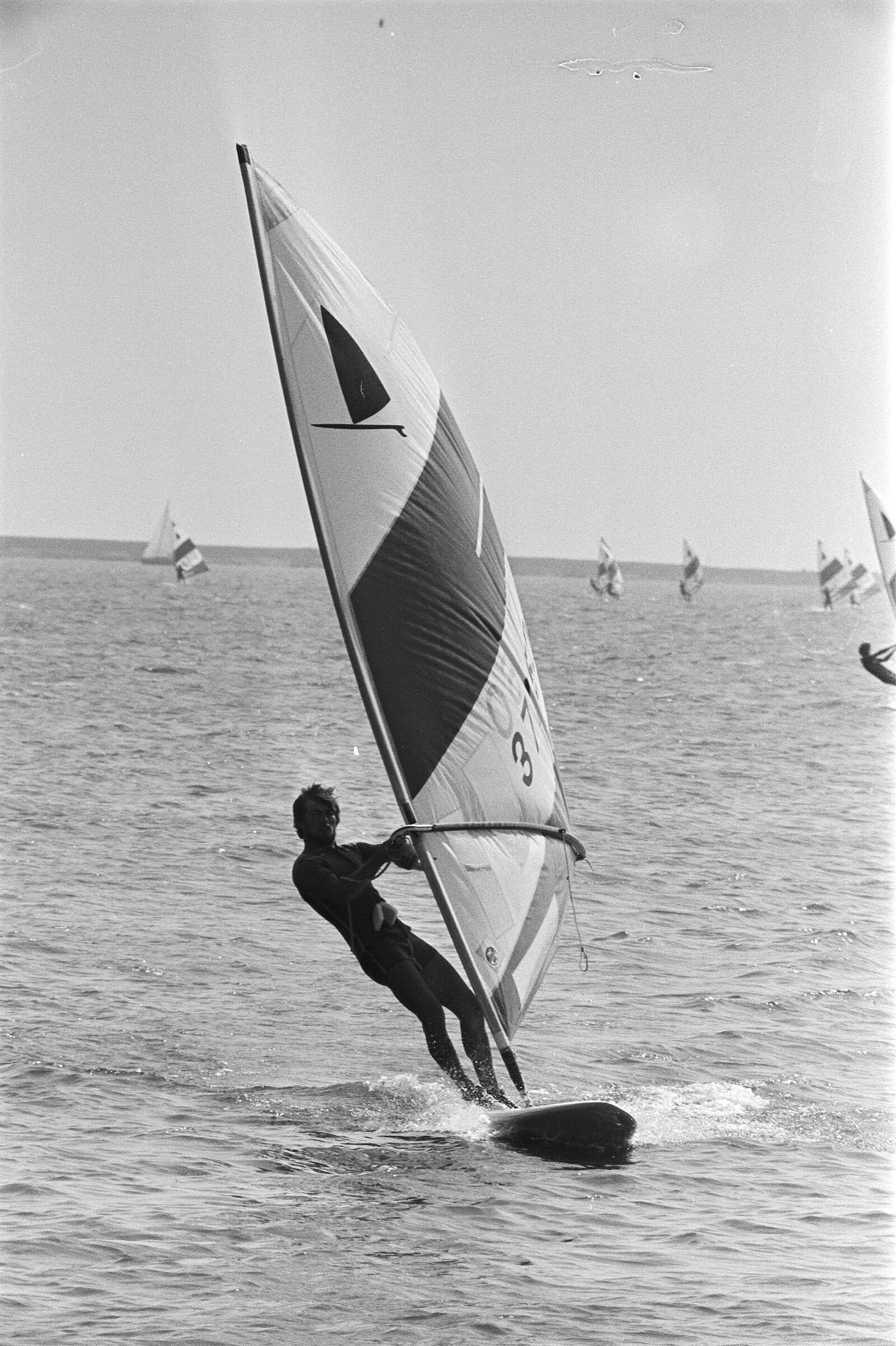 European Windsurfing Championships, Volendam — single rider: Single windsurfer on an early One-Design board, hanging off the wishbone, sail filling the upper half; portrait orientation.